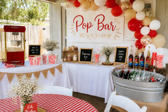 Classic red and white Ready to Pop baby shower setup with popcorn and soda bar