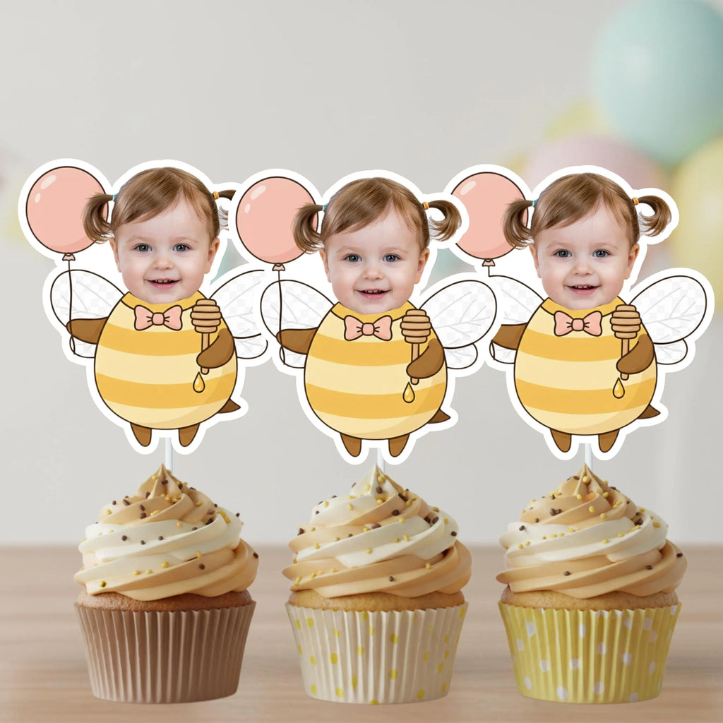 Three cupcakes with decorative toppers of a child in a bee costume on a light background.