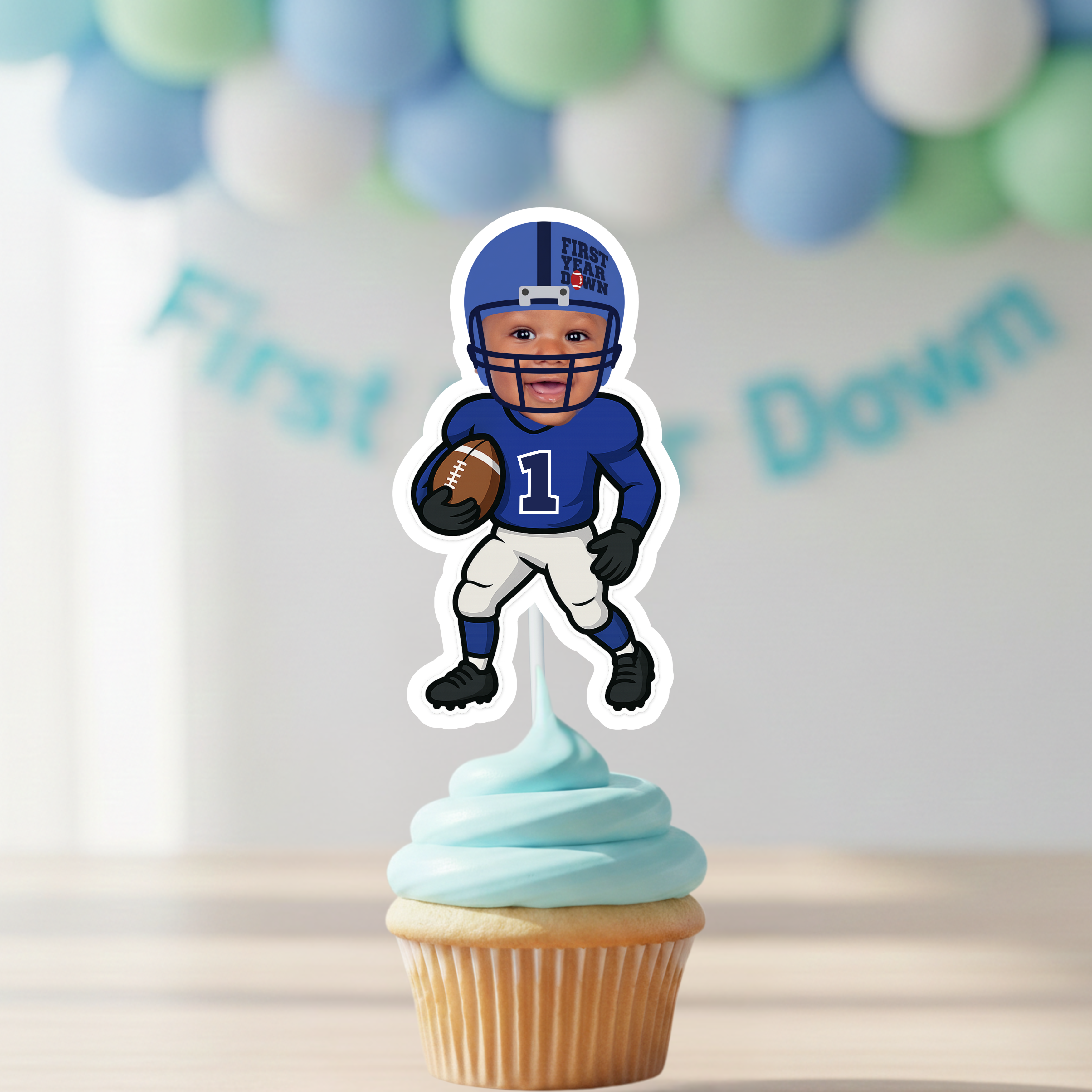 A custom First Year Down football cupcake topper with a baby photo is placed on a pastel blue frosted cupcake. This personalized first birthday party decoration is perfect for a football-themed baby boy celebration, cake smash photos, or sports-inspired dessert table styling. A keepsake-quality topper designed for a “One Year Down” birthday event.