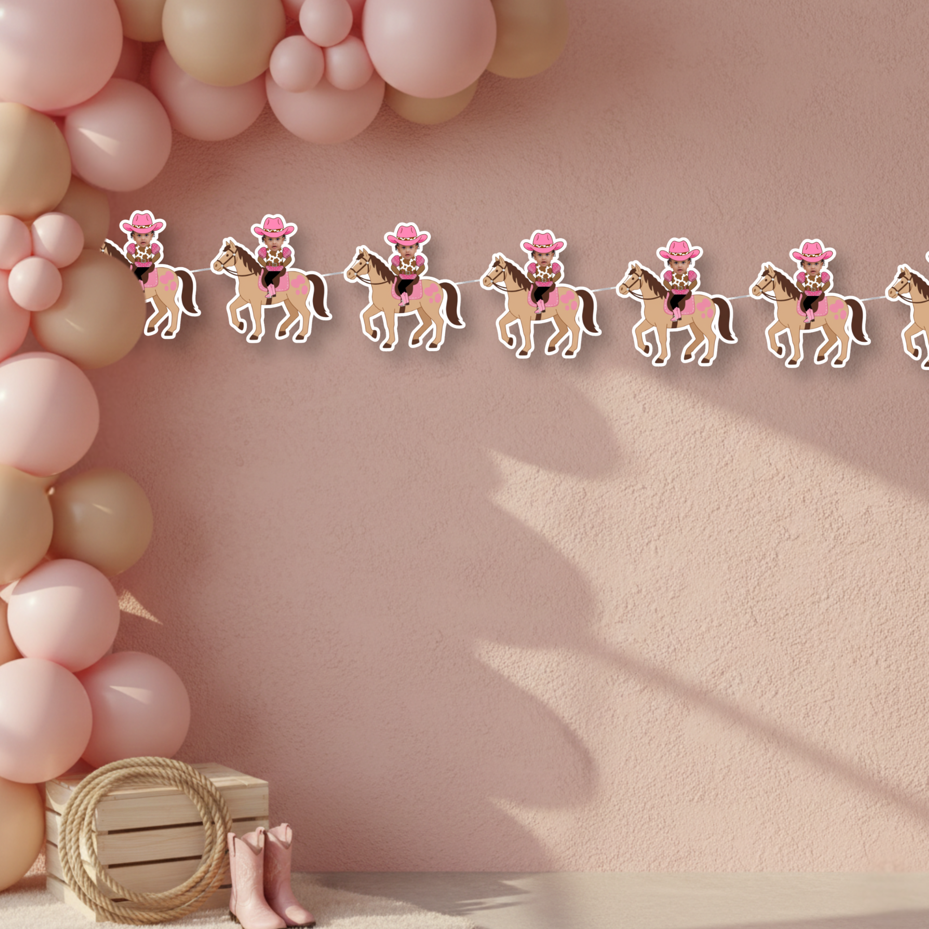 Cowgirl smash cake backdrop featuring personalized My First Rodeo photo banner on blush textured wall with western party accents. This elegant pink cowgirl birthday setup highlights the custom photo banner as a statement piece for smash cake photos and little rodeo celebrations.