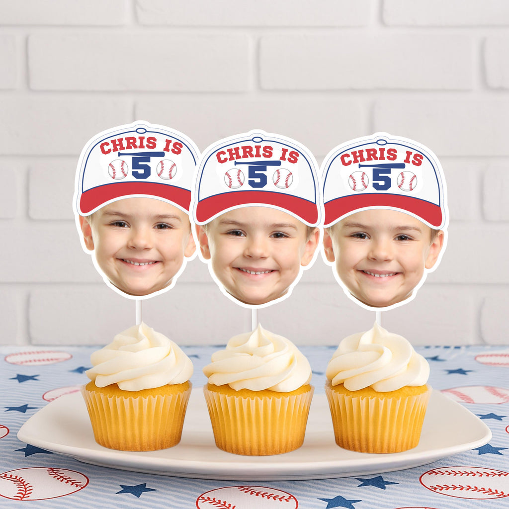 Three cupcakes with personalized face cutouts and a child's name and age on a white plate against a brick wall background.