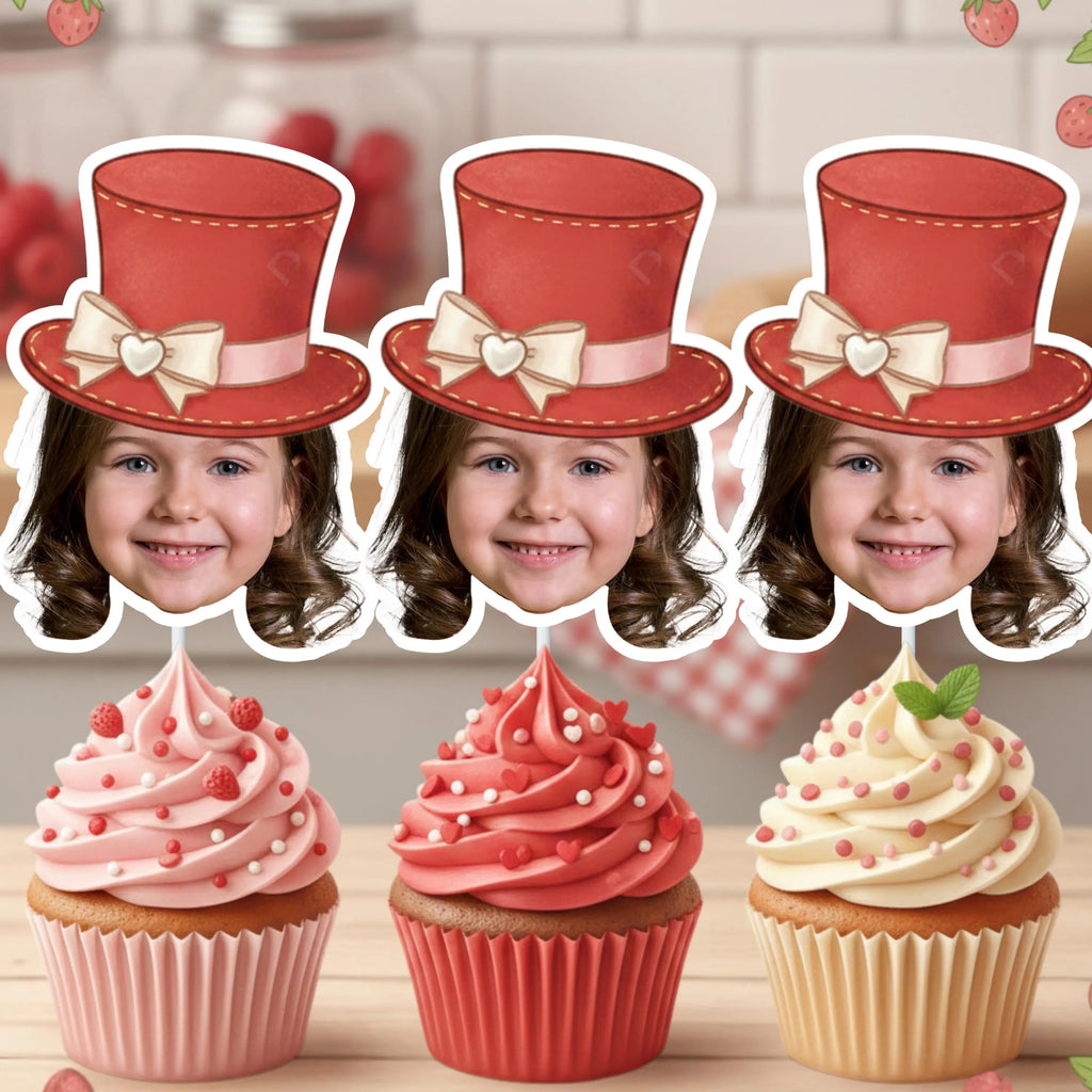 Three cupcakes with red hats and pink frosting on a wooden surface.