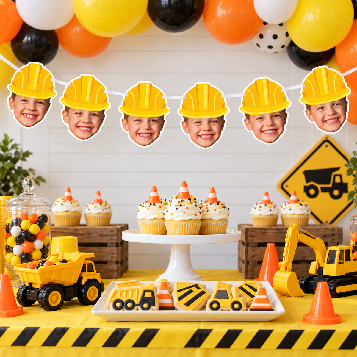 Personalized construction birthday face banner with yellow hard hats displayed at a construction themed party with dump truck excavator cupcakes traffic cones and caution decorations