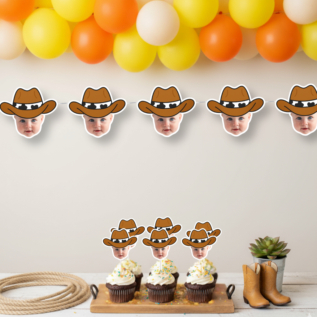 Western party scene with personalized cowboy baby face cupcake toppers on cake stand beneath matching photo banner and orange, yellow, and white balloon garland. Styled with toy horses and rope for cowboy first birthday, rodeo themed baby shower, and wild west celebration décor. Custom photo cupcake decorations.