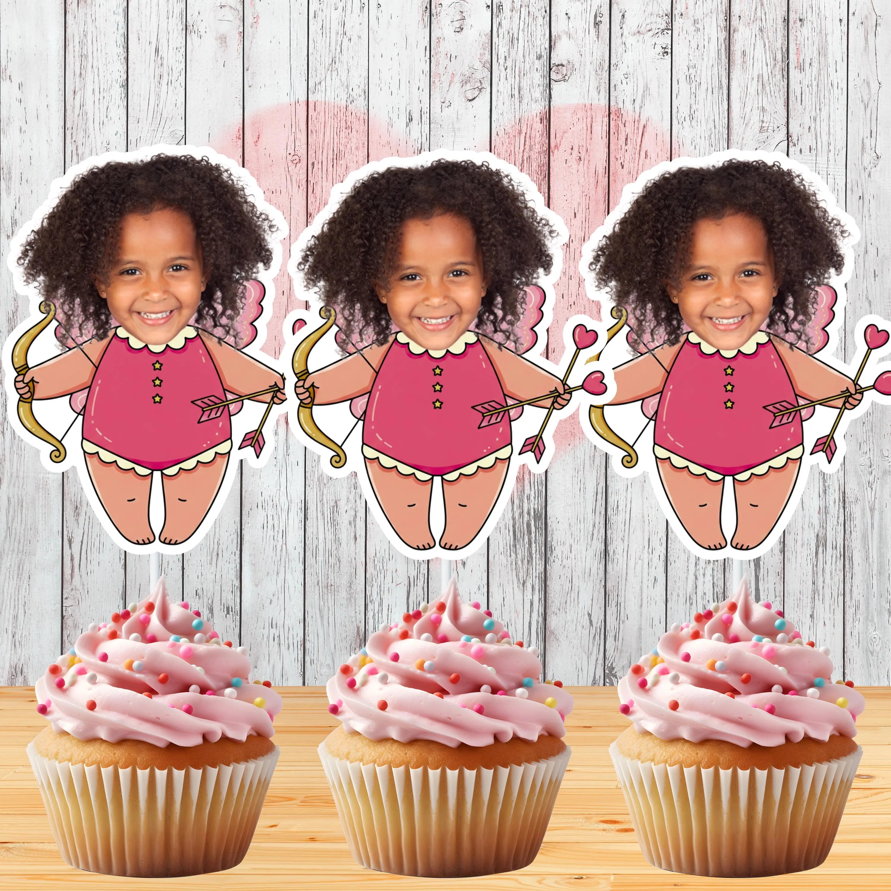 Three identical cutouts of a girl in a pink outfit with a bow and arrow, placed above cupcakes with pink frosting.