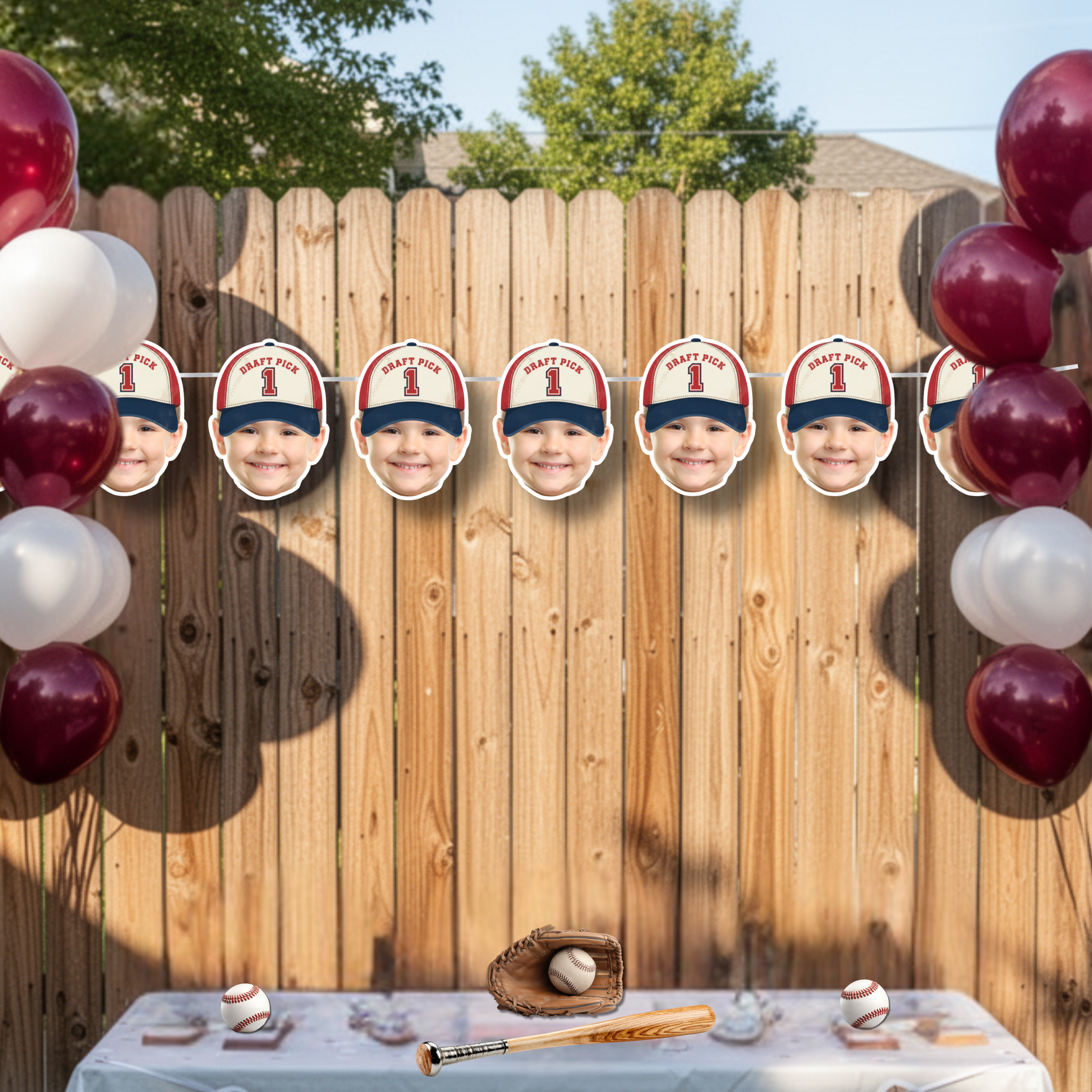 Custom photo baseball banner featuring Rookie of the Year Draft Pick 1 design displayed on backyard wooden fence with red and white balloon clusters, baseball bat and glove decor for outdoor little slugger birthday party backdrop.