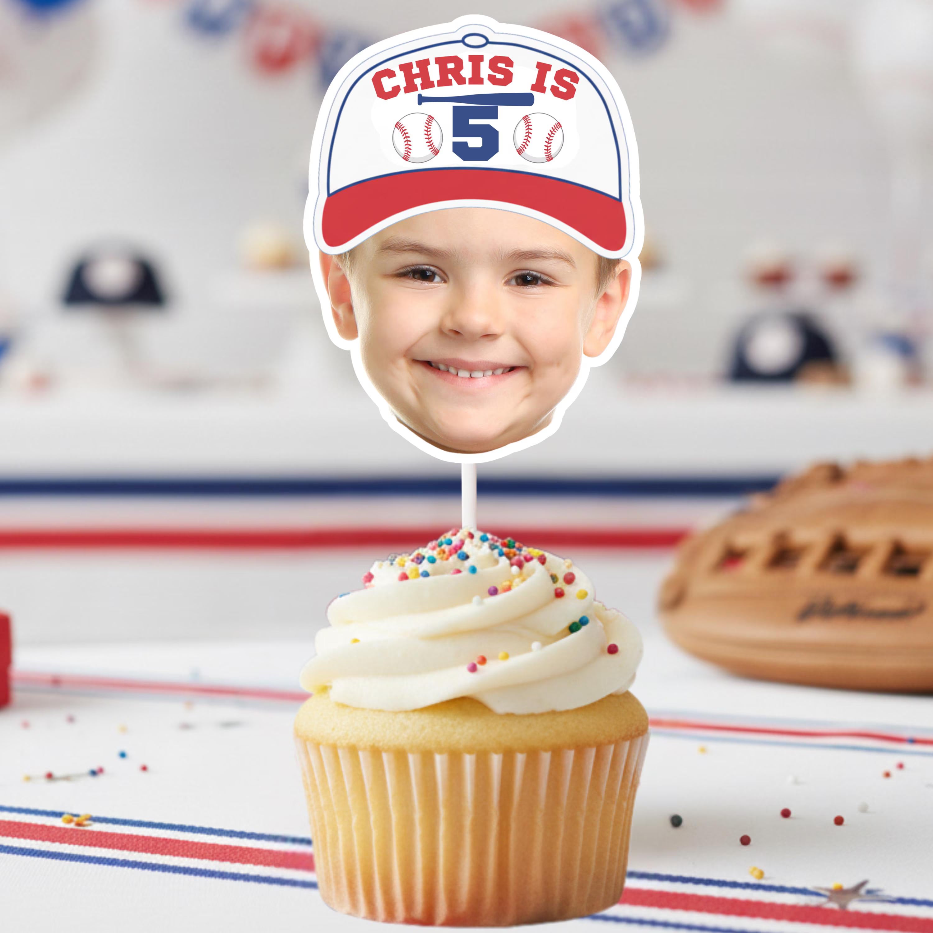 Cupcake with a personalized face cutout and baseball-themed hat on a sports-themed background