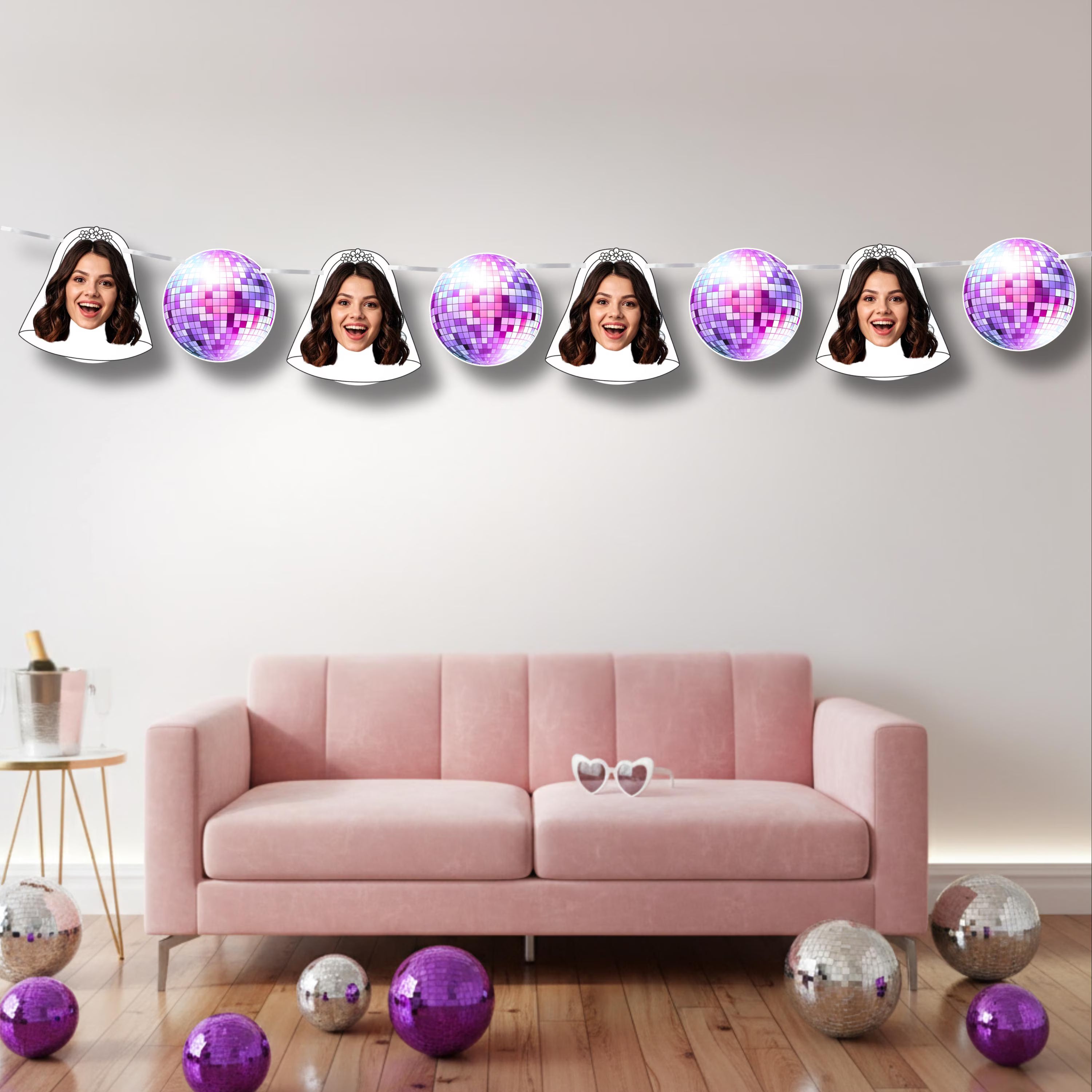 Decorative string with faces and disco balls hanging above a pink sofa.