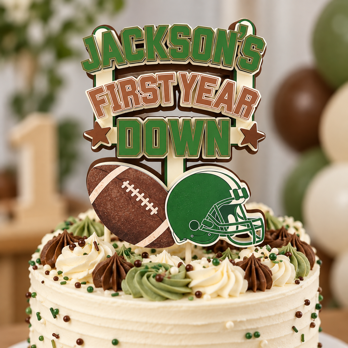 Close up view of personalized First Year Down football cake topper on a birthday cake showing layered cardstock details football and green helmet