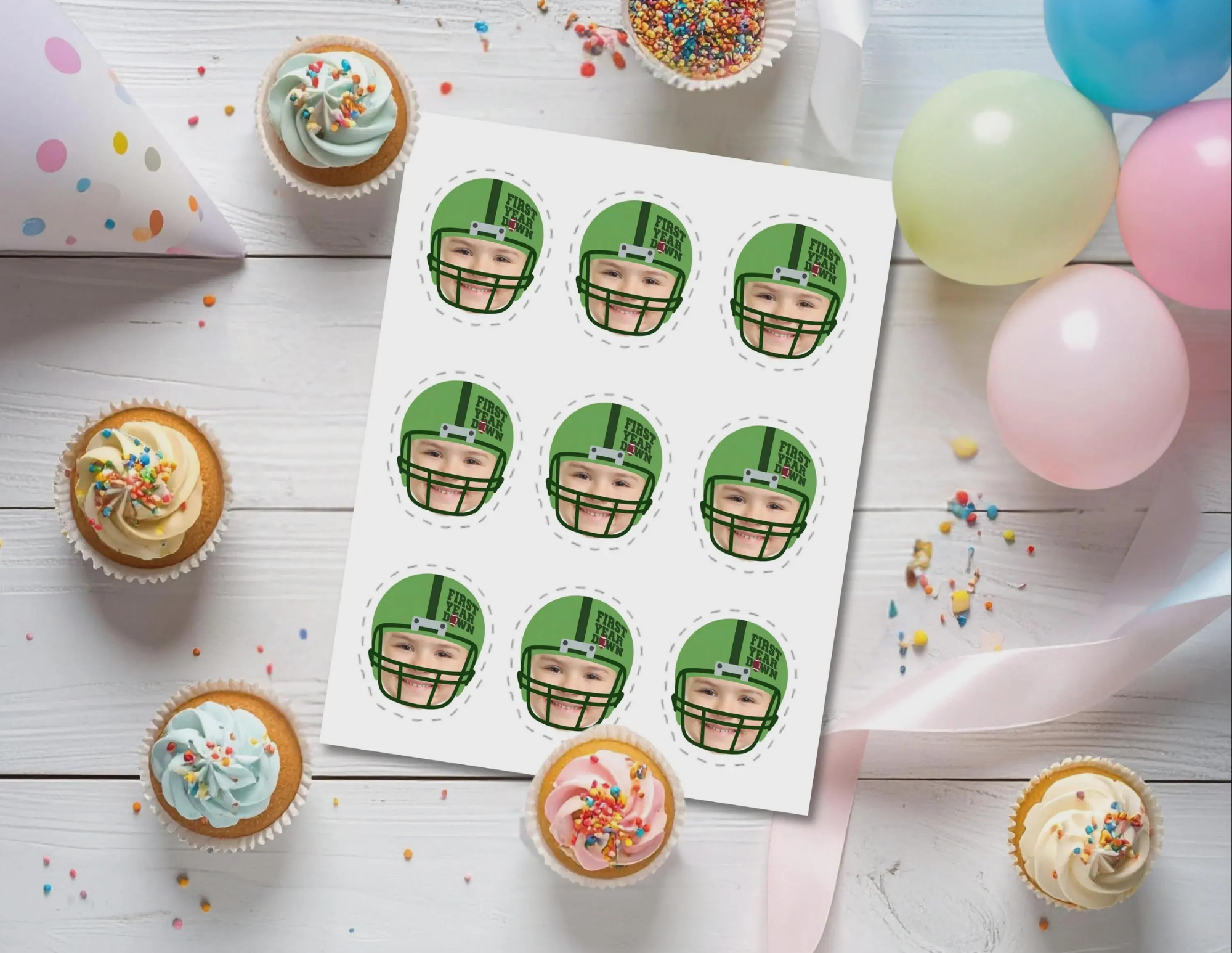 Printable sheet of personalized First Year Down football photo cupcake toppers with a child’s face in a green helmet, displayed with cupcakes and party balloons.