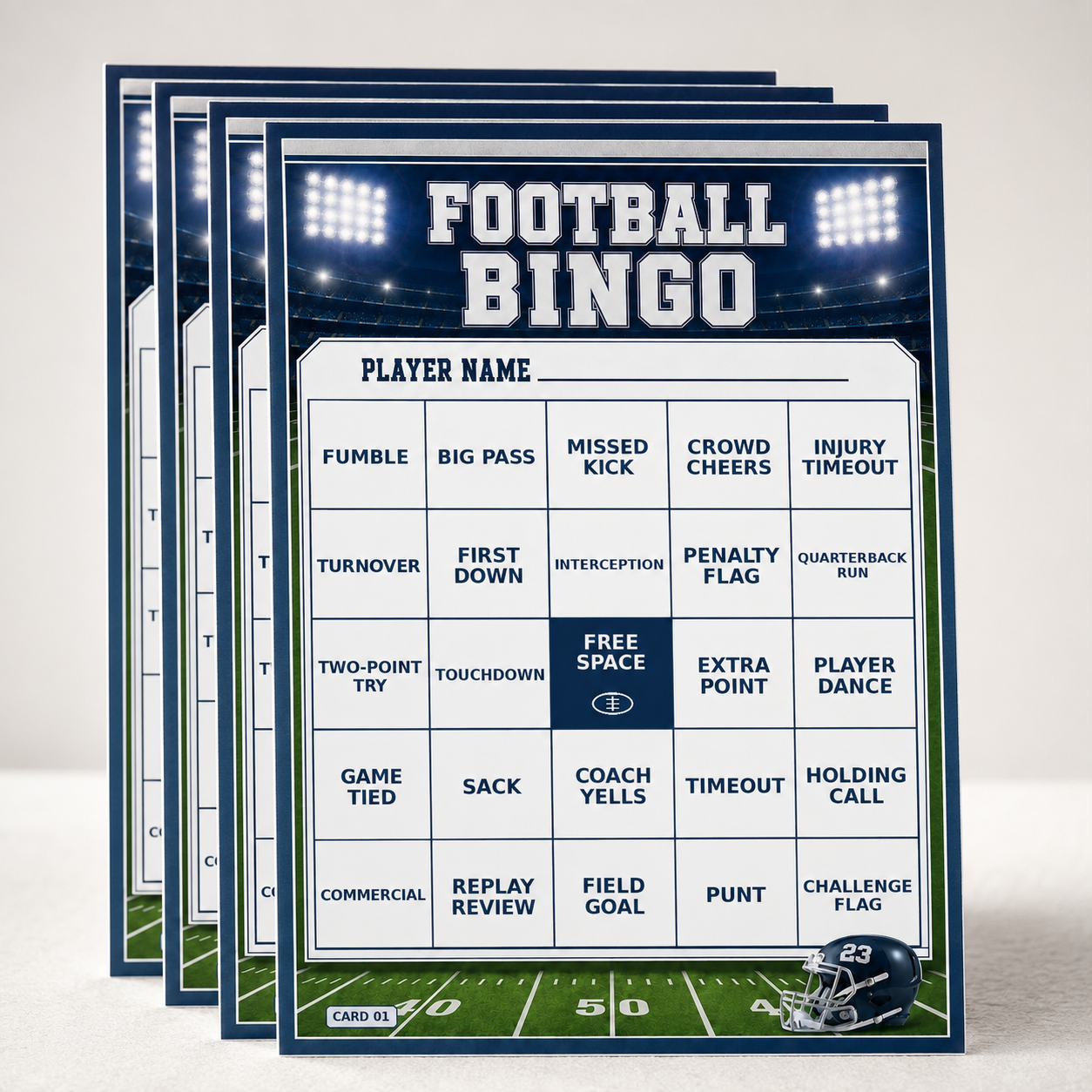 A stack of football-themed bingo cards displayed on a light beige surface. The front card shows a white grid with blue text on a dark blue stadium-light background, with a football field strip along the bottom and a navy helmet graphic in the lower right corner.