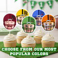 Football themed first birthday cupcake toppers showing popular helmet color options including red, yellow, green, blue, and orange displayed on vanilla cupcakes with white frosting. First Year Down sports party decorations styled for baby boy football birthday celebration with customizable team colors. Image text reads, "Choose from our most popular colors". 