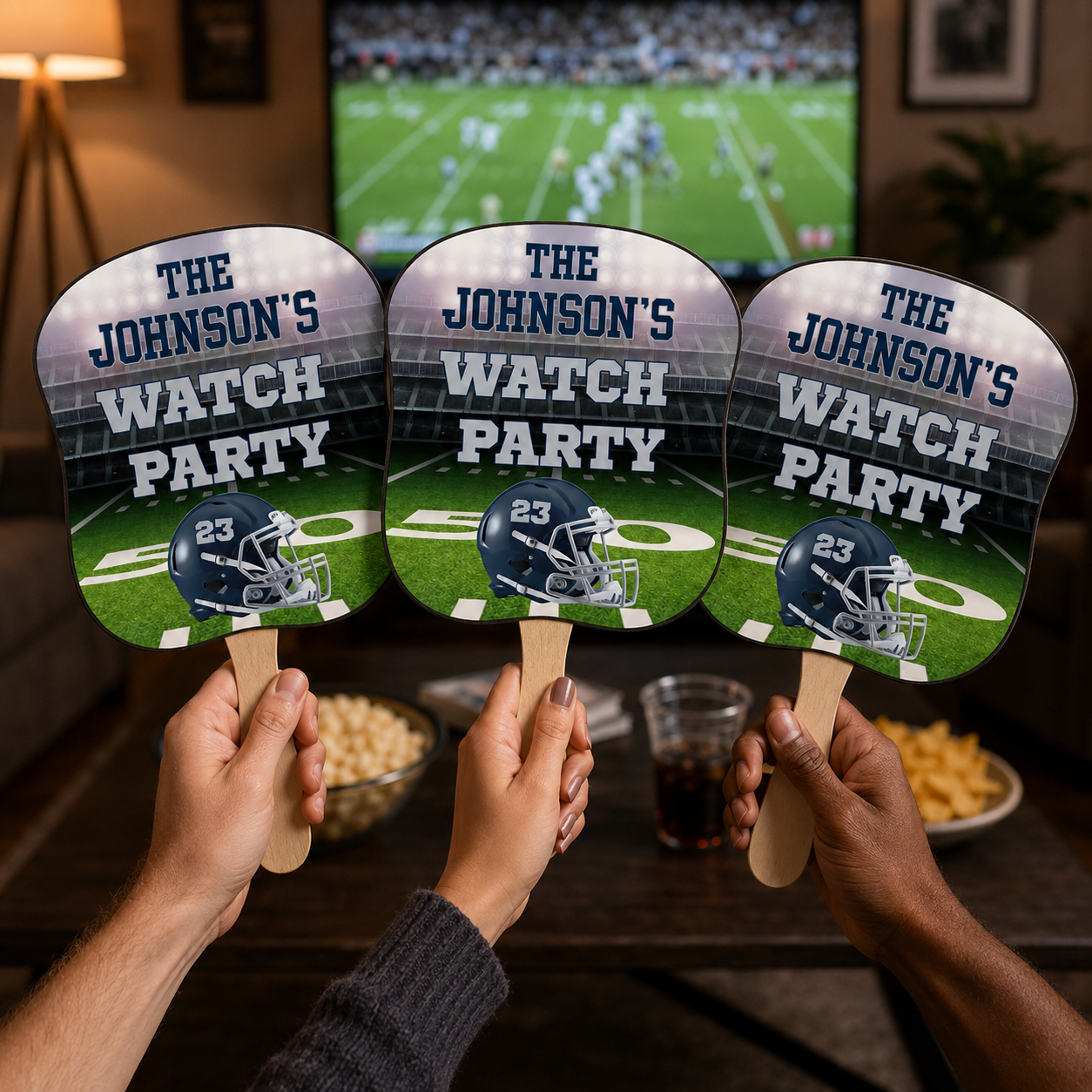 Guests holding personalized football rally fans during a home watch party with custom family wording and jersey number 23