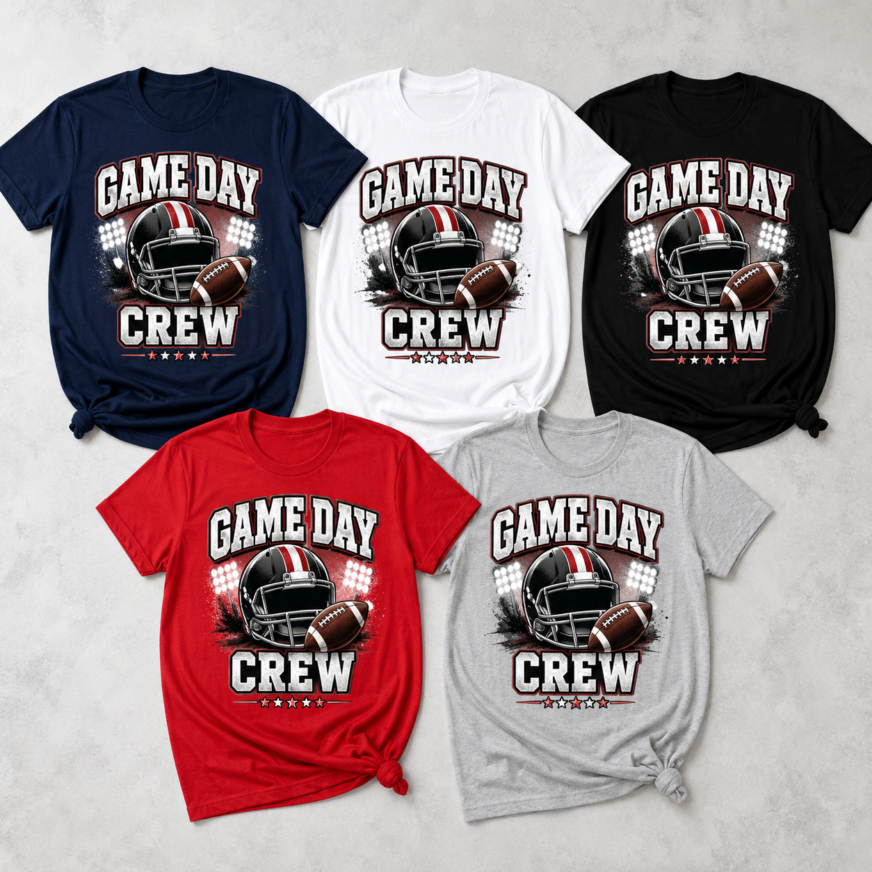 Five short-sleeve graphic T-shirts arranged on a light gray textured background, shown in navy, white, black, red, and heather gray. Each shirt features a football helmet and football graphic with the text 'GAME DAY CREW' and '2025'.