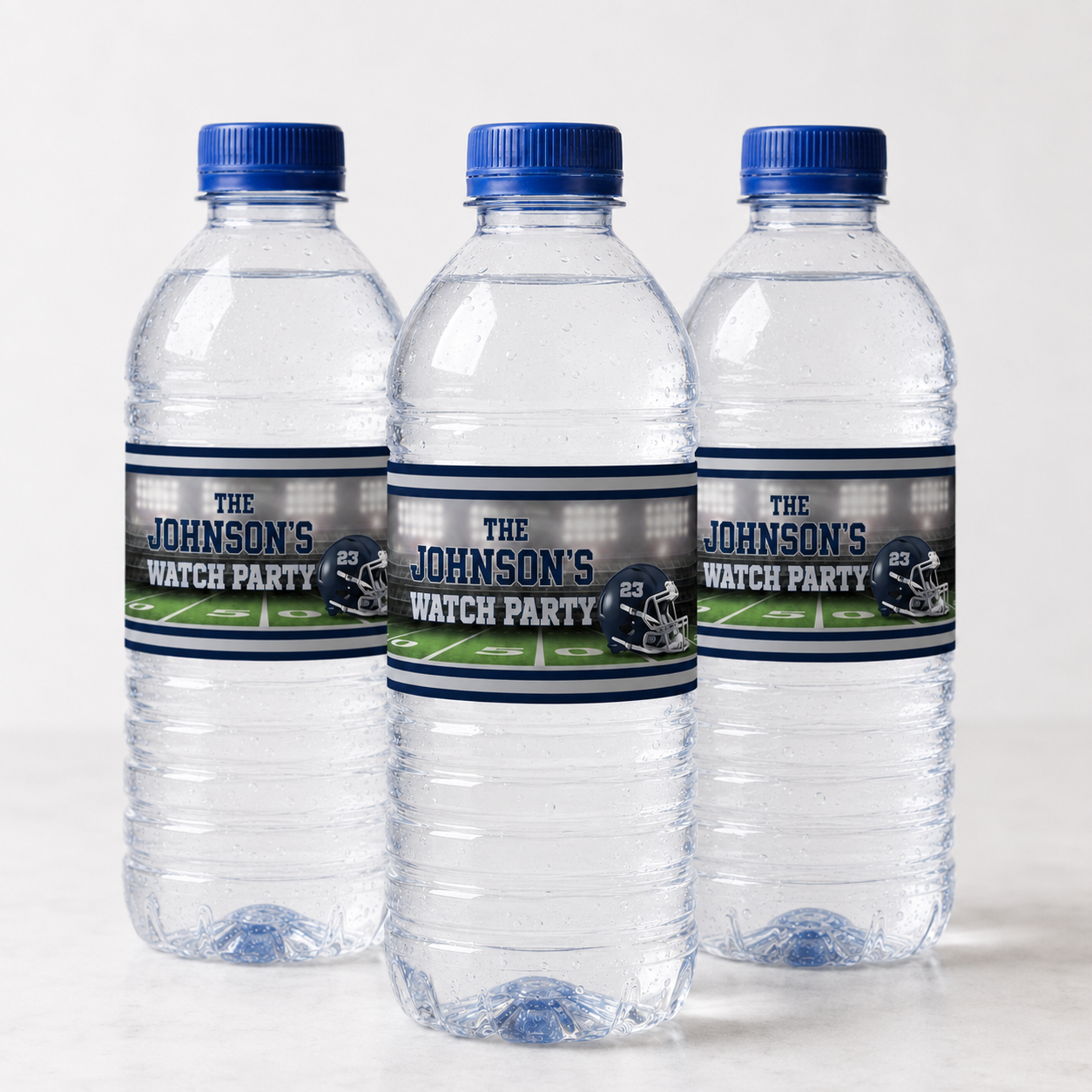 Three standard water bottles featuring personalized navy and silver football party labels with a stadium design and helmet number 23.