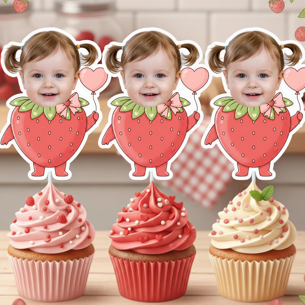 Three strawberry-themed cupcake toppers with a child's face on a wooden surface.