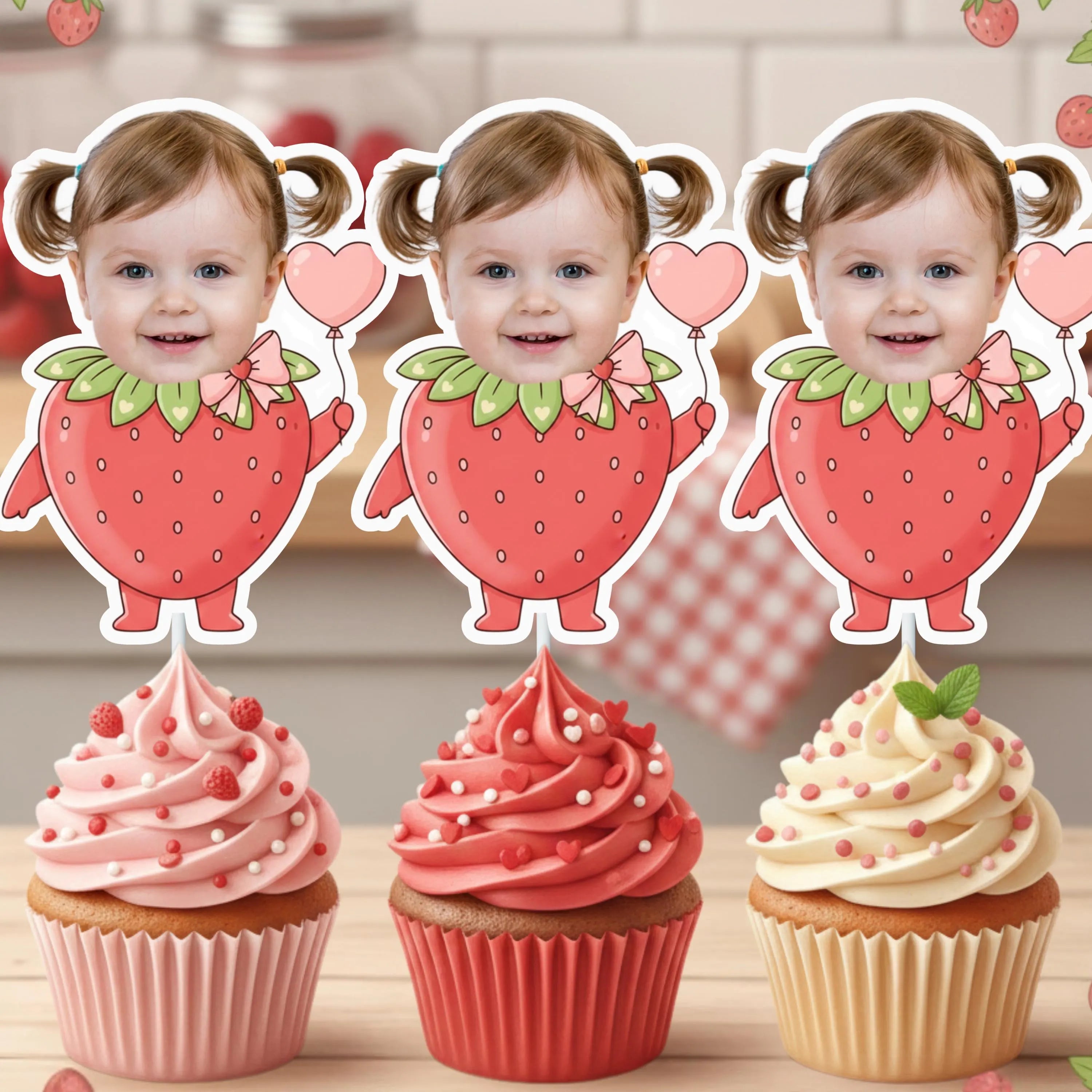 Three strawberry-themed cupcake toppers with a child's face on a wooden surface.