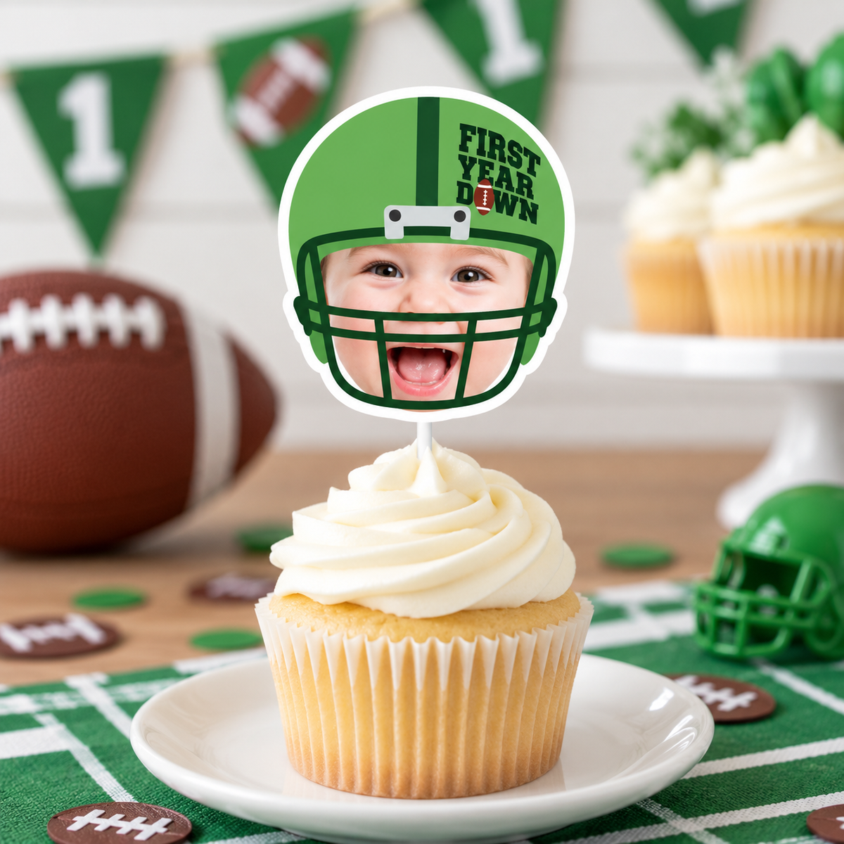 Close up of a personalized First Year Down football photo cupcake topper featuring a child face in a green football helmet for a first birthday party