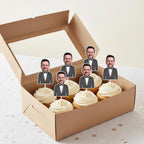 Box of Groom cupcakes with face cutouts of a man in a suit on top. 