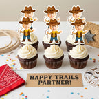 Cupcakes with cowboy-themed toppers on a table with 'Happy Trails Partner!' sign.