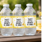 Three water bottles with personalized labels on a wooden surface outdoors.