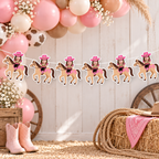 Personalized My First Rodeo cowgirl photo banner displayed on a white wood wall with pink balloons cowboy boots rope and rocking horse for a western first birthday backdrop