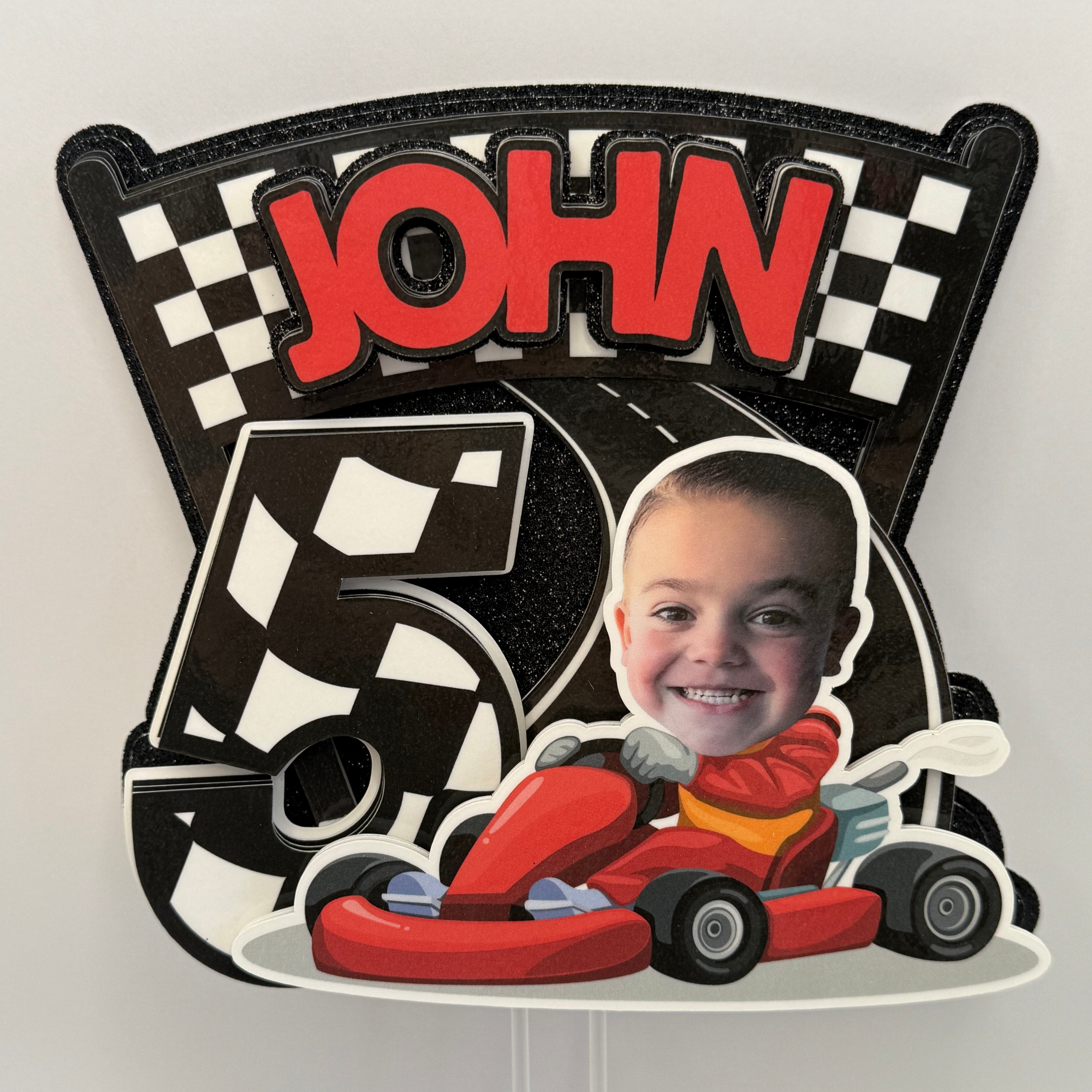 Children's birthday party decoration with a red car, checkered pattern, and 'JOHN 5' text.