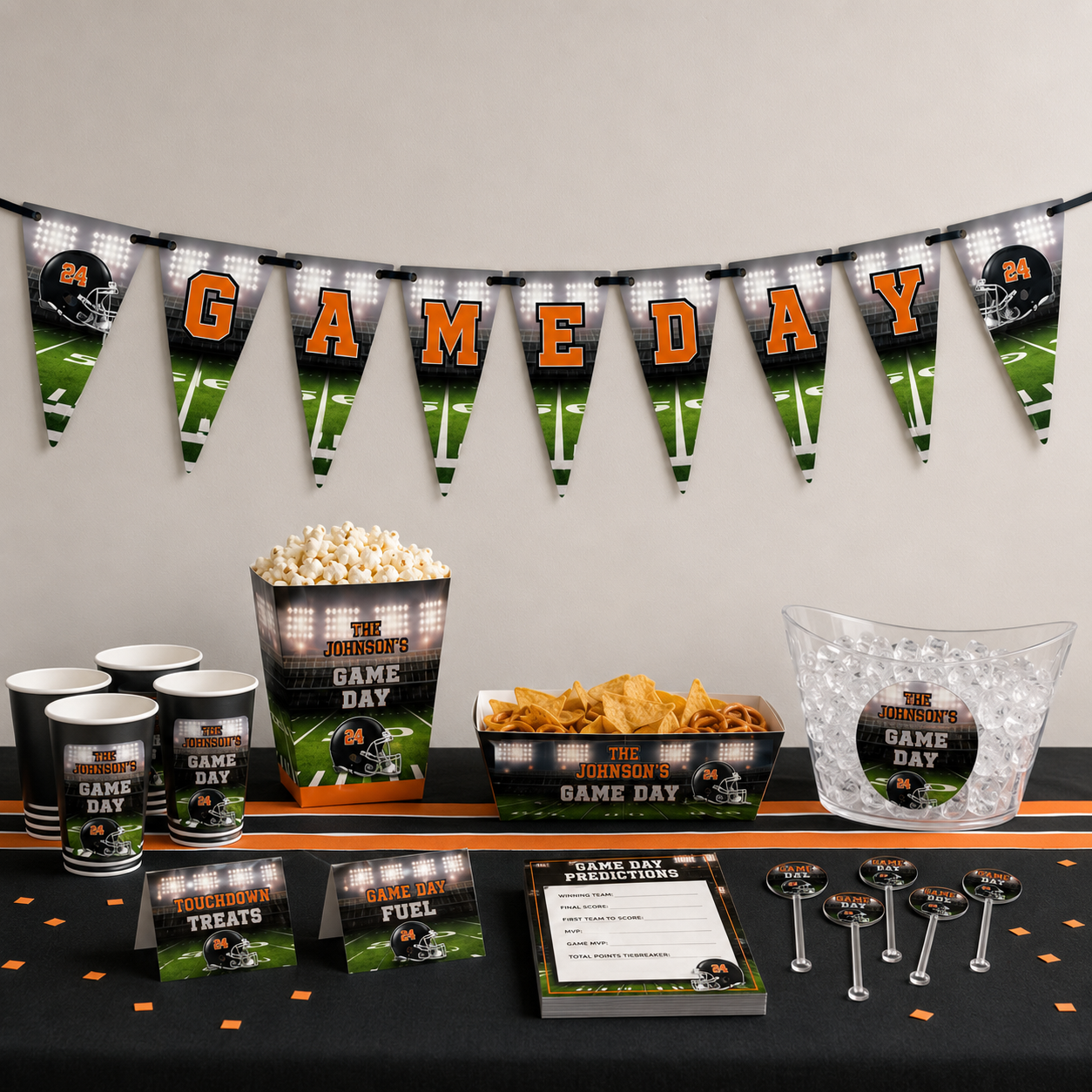 Orange and black Game Day football banner displayed with matching cups, popcorn box, snack tray, ice bucket, game cards and drink stirrers.