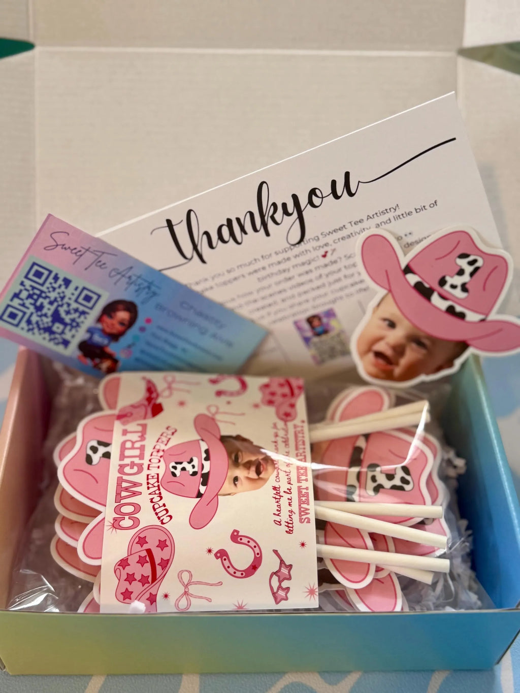 Box with pink cowgirl-themed items including a card, stickers, and a baby photo.