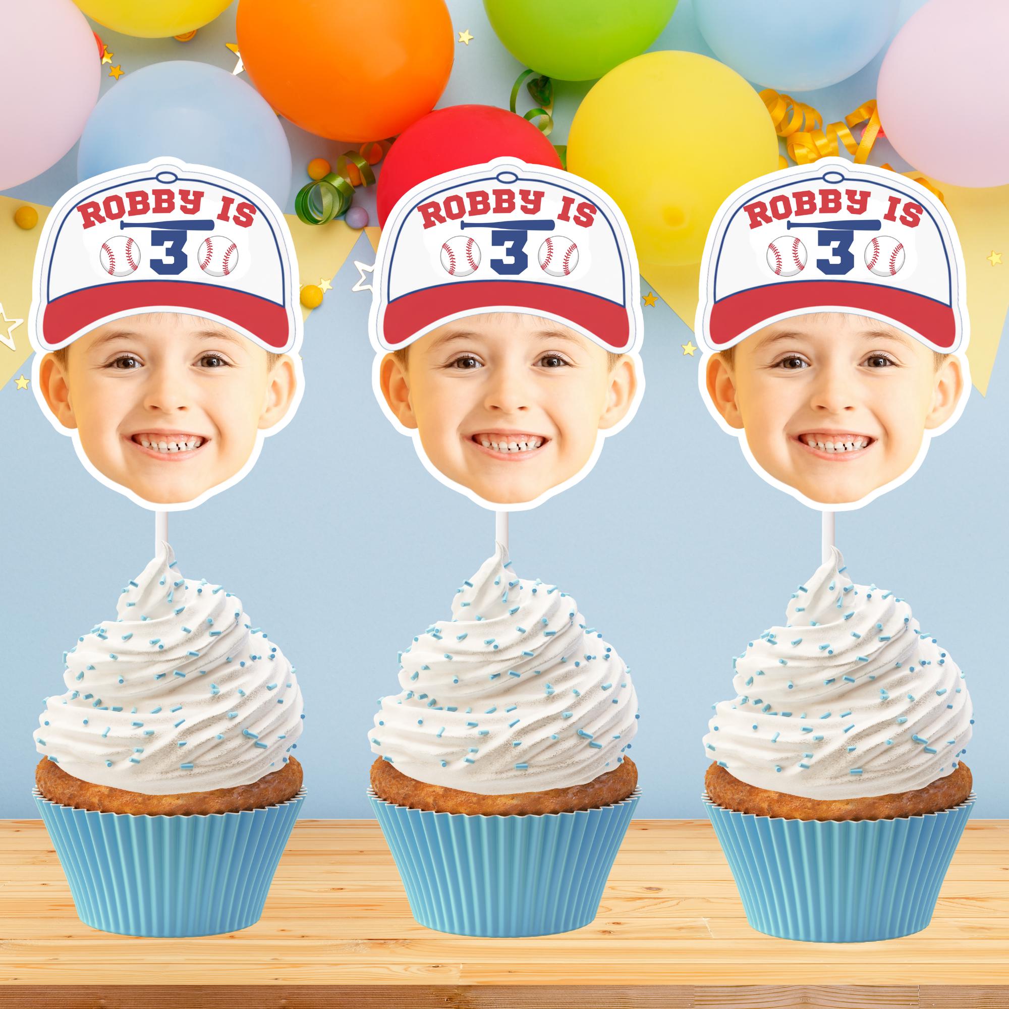 Three cupcakes with white frosting and blue wrappers, each topped with a decorative hat featuring 'Robby is 3' text against a colorful balloon background.
