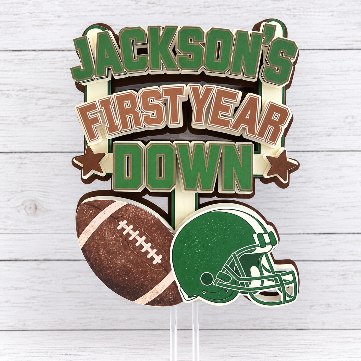 Personalized layered cardstock First Year Down football cake topper with child name football green helmet and brown star accents