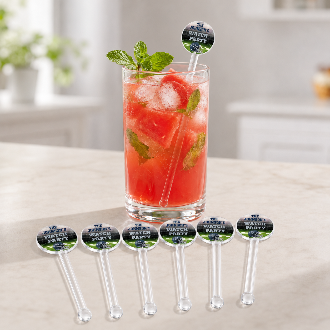 Personalized clear football drink stir sticks displayed with an iced berry drink in a navy and silver watch party design.