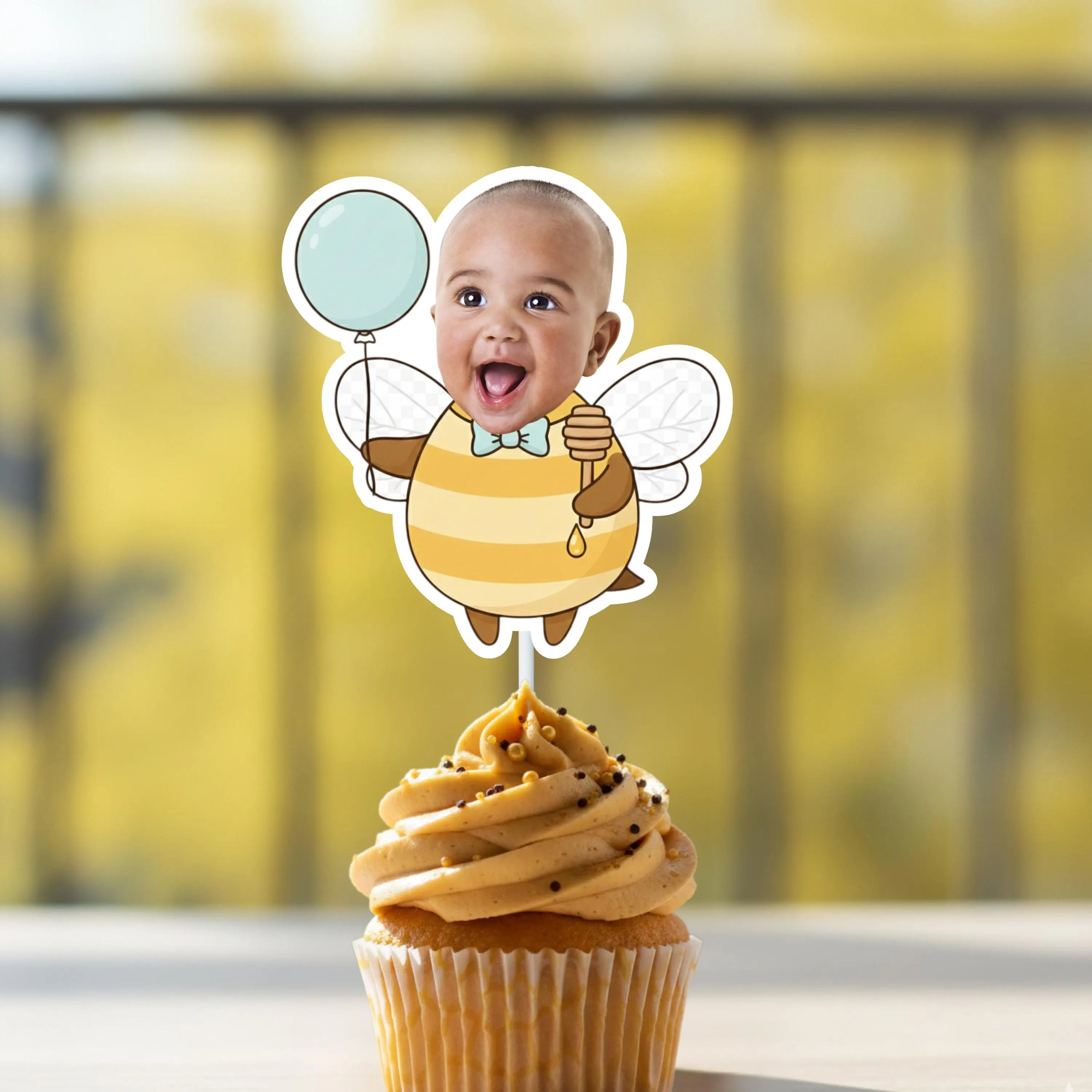 Happy baby boy face holding a balloon on a honey bee body cupcake topper