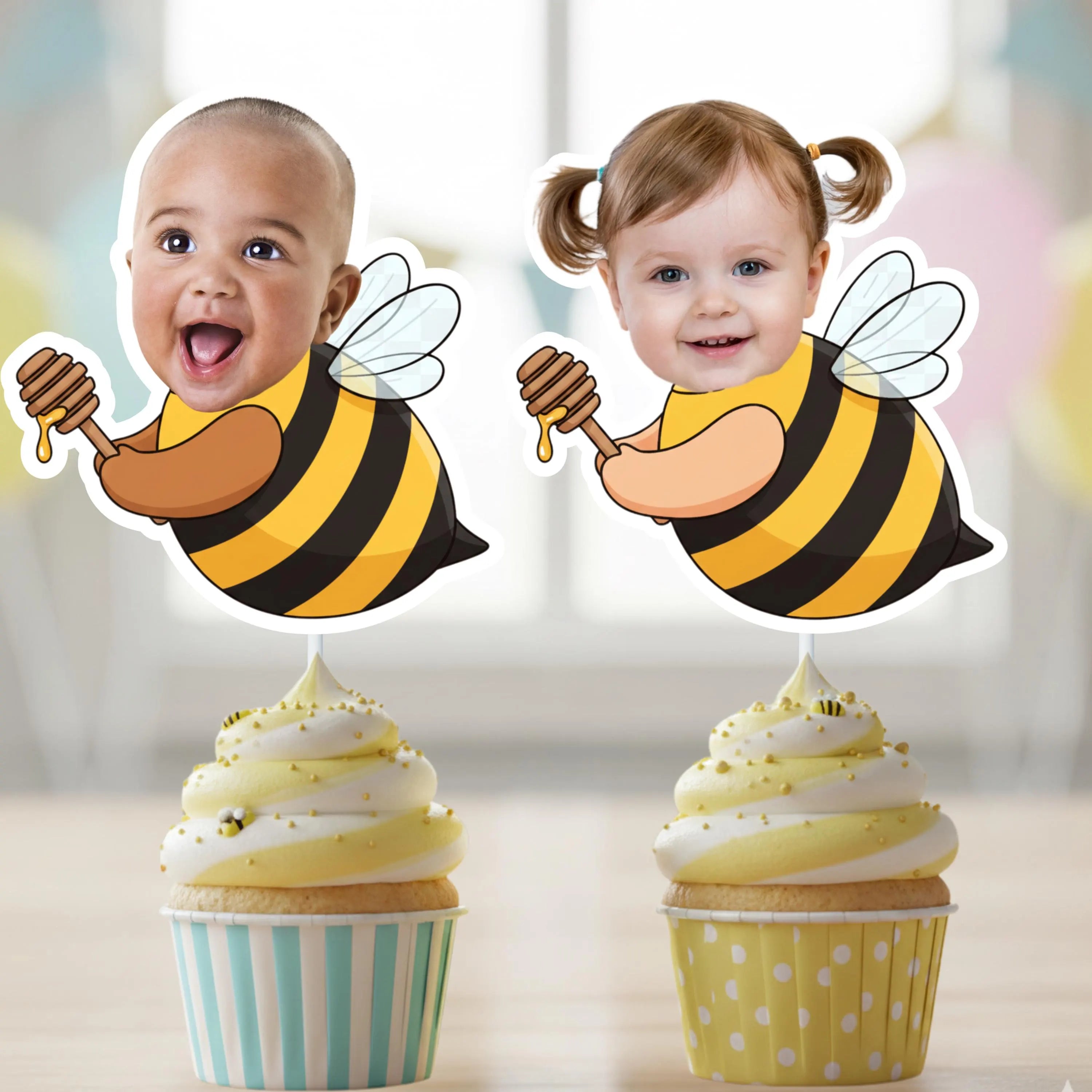 Two cupcake toppers with children's faces and bee designs on a blurred background.