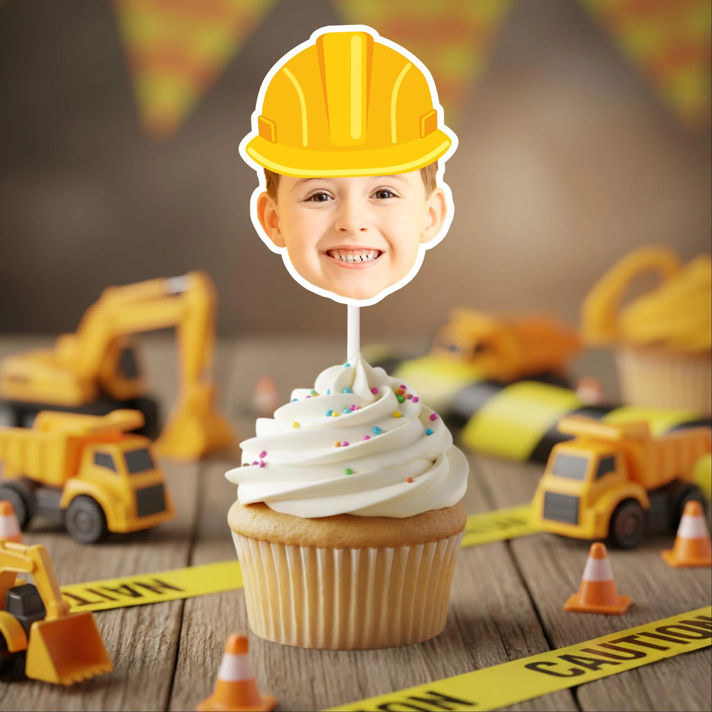 Cupcake with a construction-themed topper and toy construction vehicles on a wooden surface.