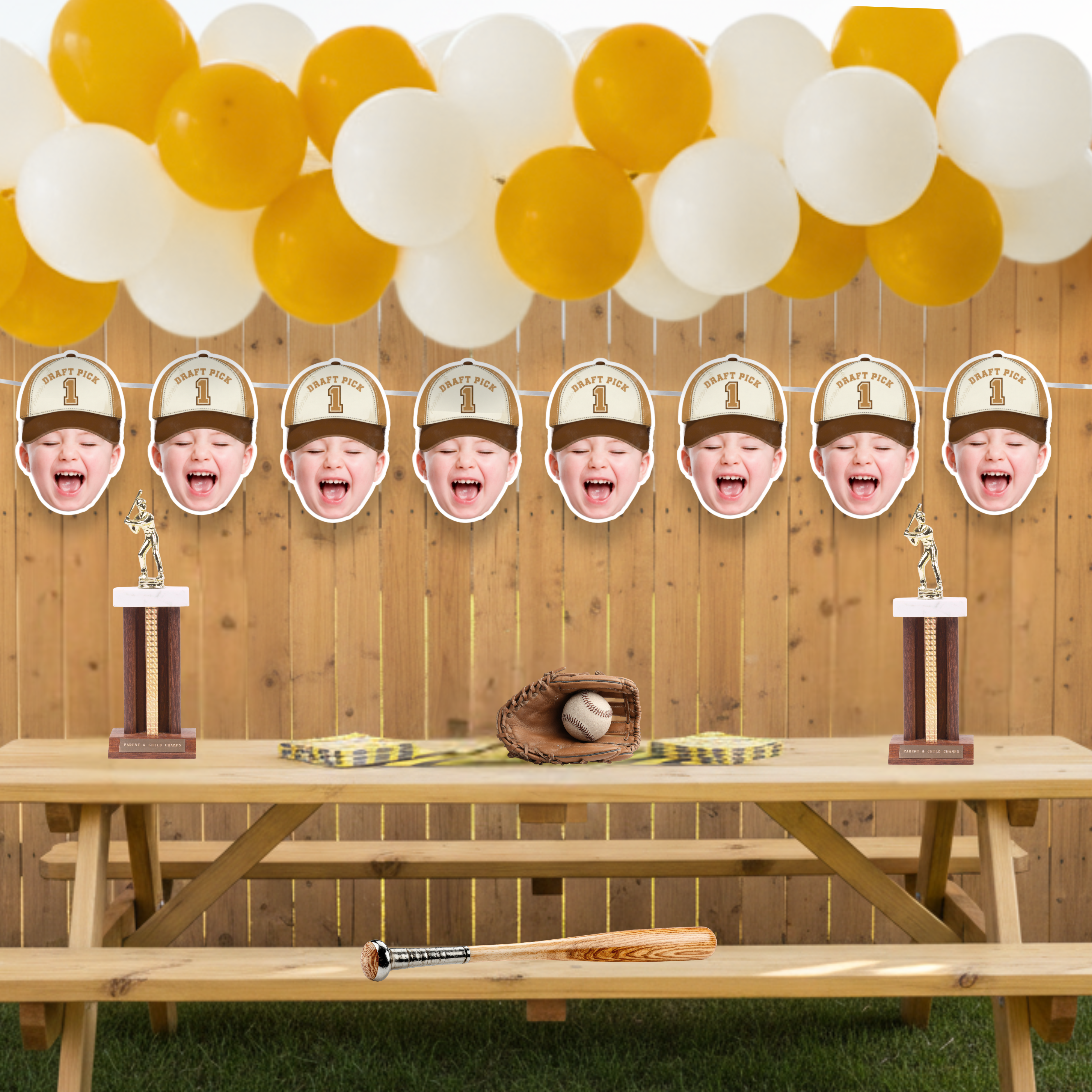 Personalized photo baseball banner featuring Rookie of the Year Draft Pick 1 design displayed on a backyard wooden fence with yellow and cream balloon garland, baseball glove and bat decor, and dessert table styling for a baseball first birthday party.