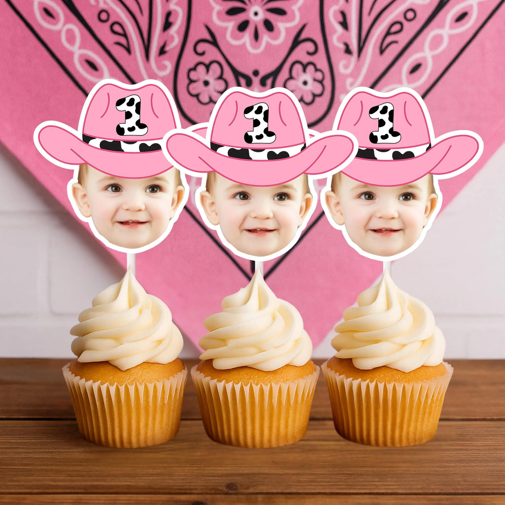 Three cupcakes with pink cowboy hats and faces on top against a pink bandana patterned background