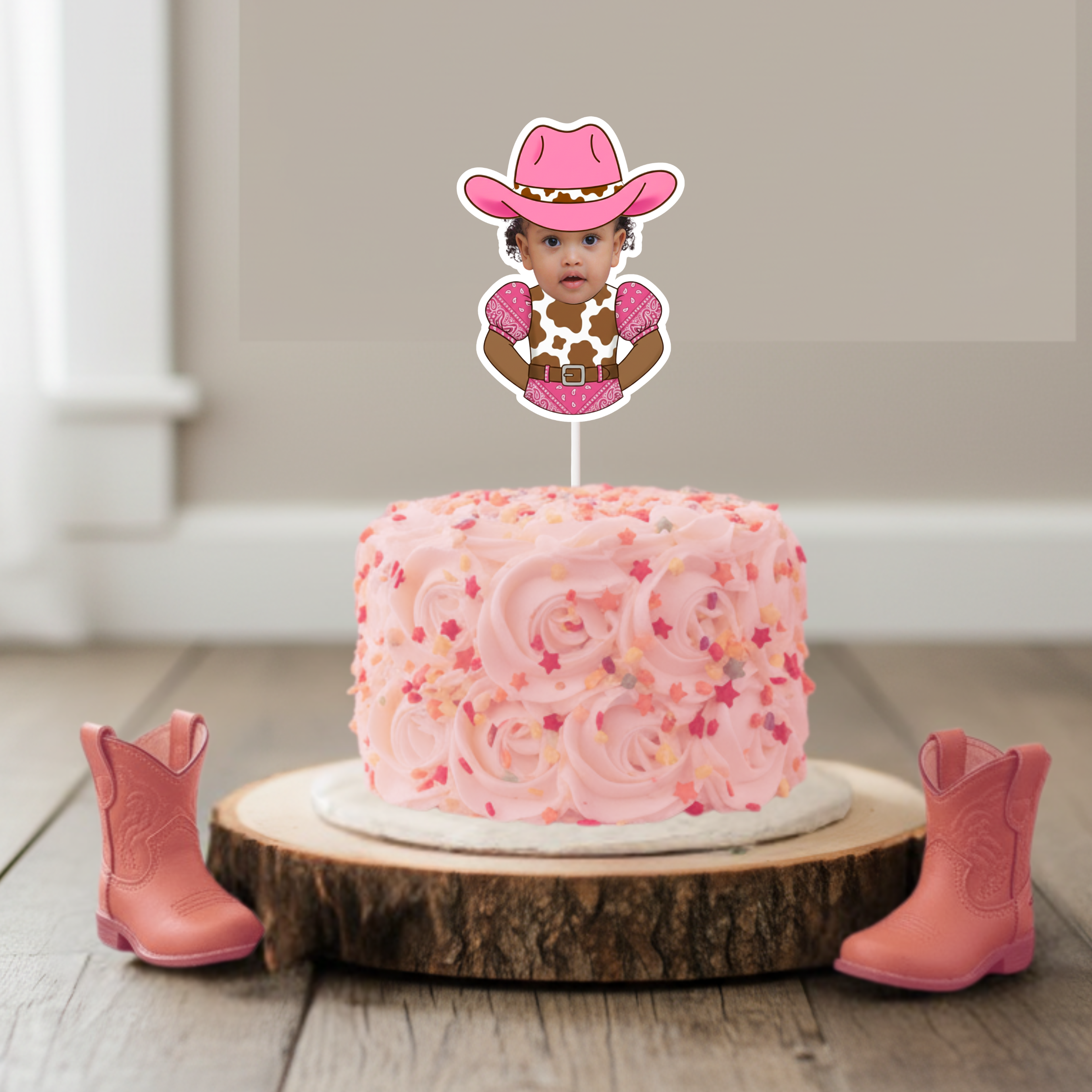 Personalized pink cowgirl cake topper featuring a baby photo dressed in a western cow print outfit with a pink cowboy hat, styled on a blush buttercream smash cake for a “My First Rodeo” first birthday party. This western themed birthday cake topper is designed for cowgirl first birthday celebrations, rodeo themed baby parties, country western baby showers, and rustic pink cowboy party décor. Displayed on a wooden cake stand with pink cowboy boots, this custom photo cake topper is ideal for smash cake photo