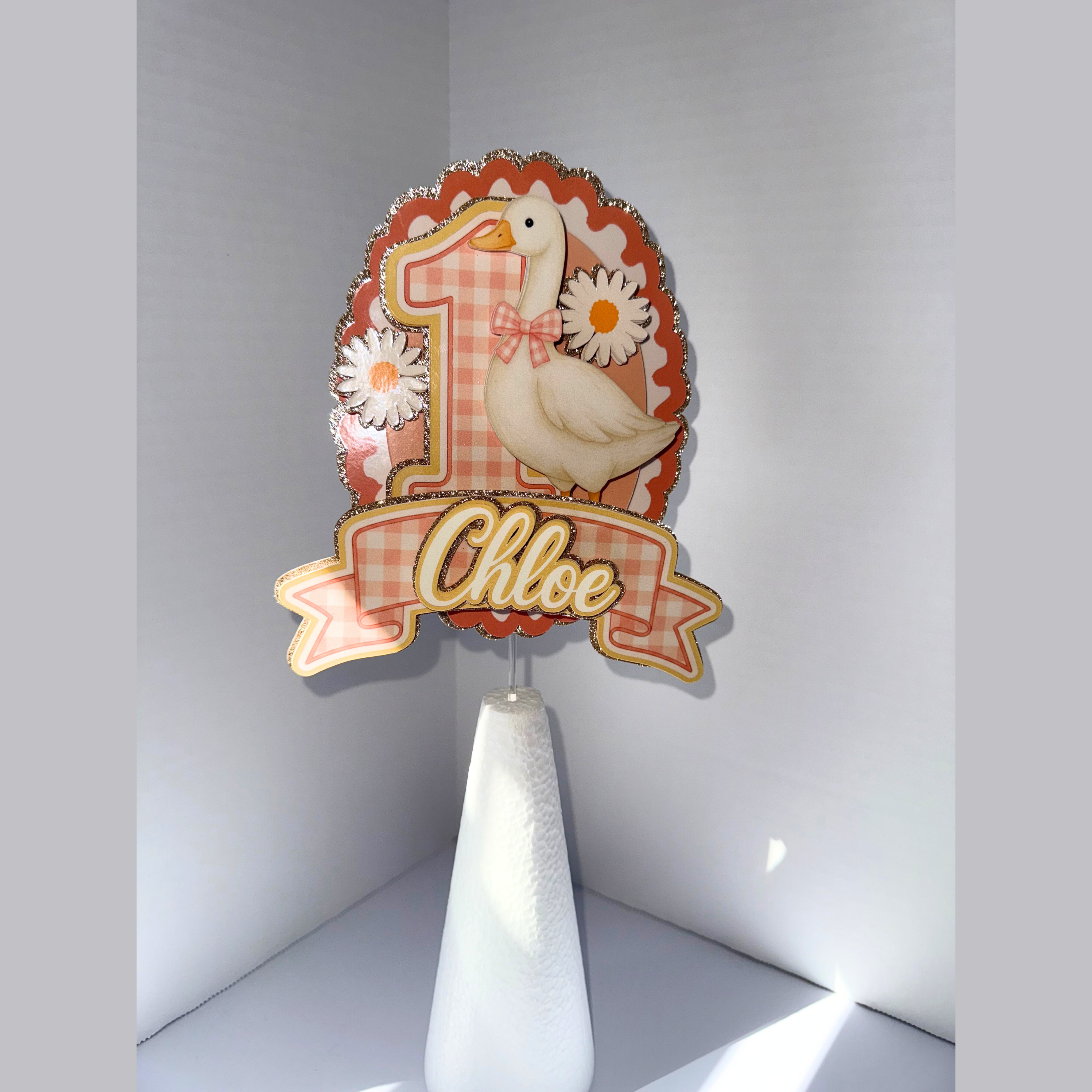 Decorative cake topper with number '1' and duck design on a white stand against a light gray background.