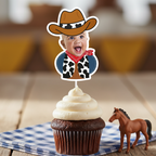 Single personalized cowboy baby photo cupcake topper displayed on chocolate cupcake with western toy horse and blue gingham napkin background. Ideal for cowboy first birthday parties, country themed baby celebrations, rodeo milestone events, and barnyard birthday décor. Custom face cupcake decoration designed to showcase the child’s photo for western party themes.
