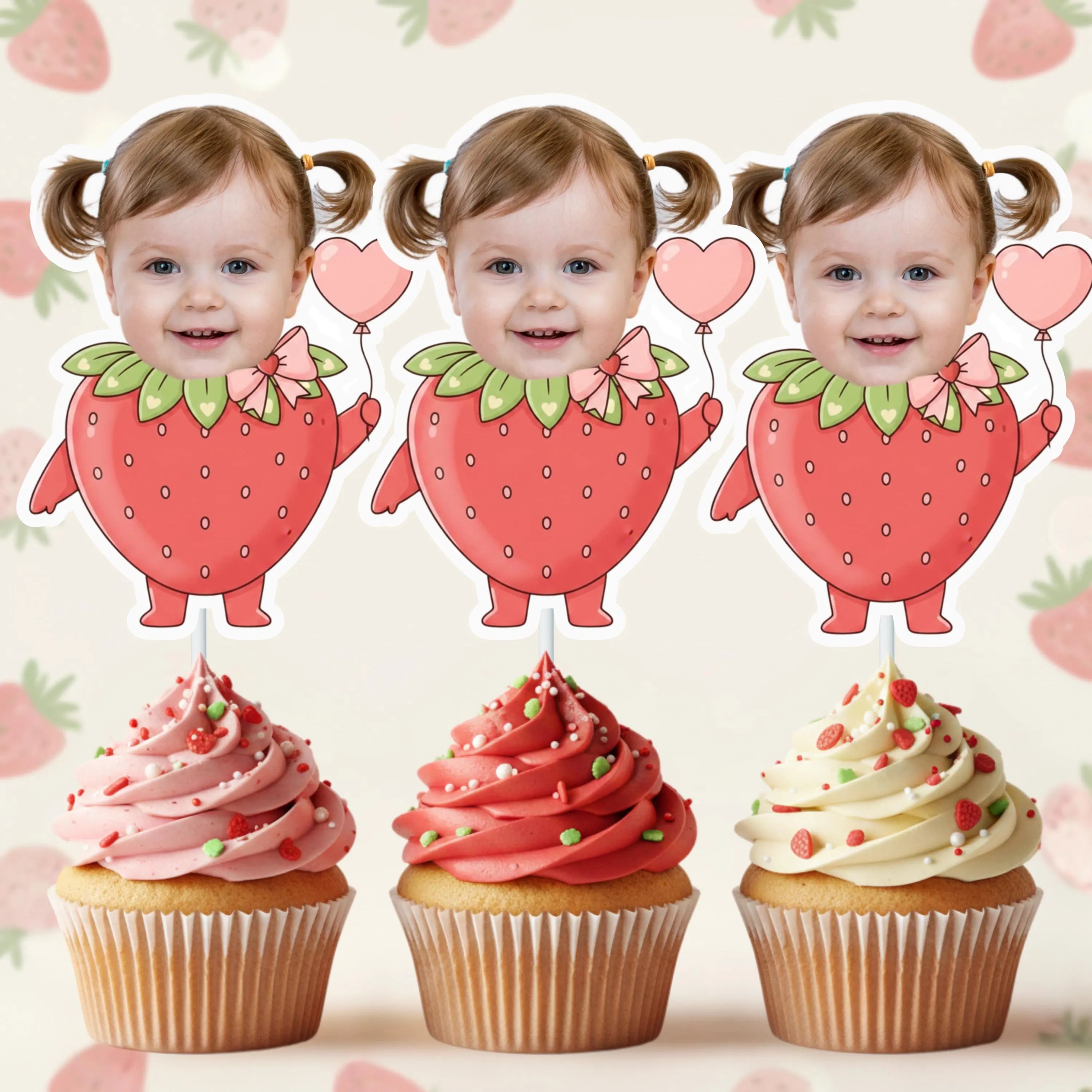 Three strawberry-shaped cupcake toppers with a child's face on a pink background with heart shapes.