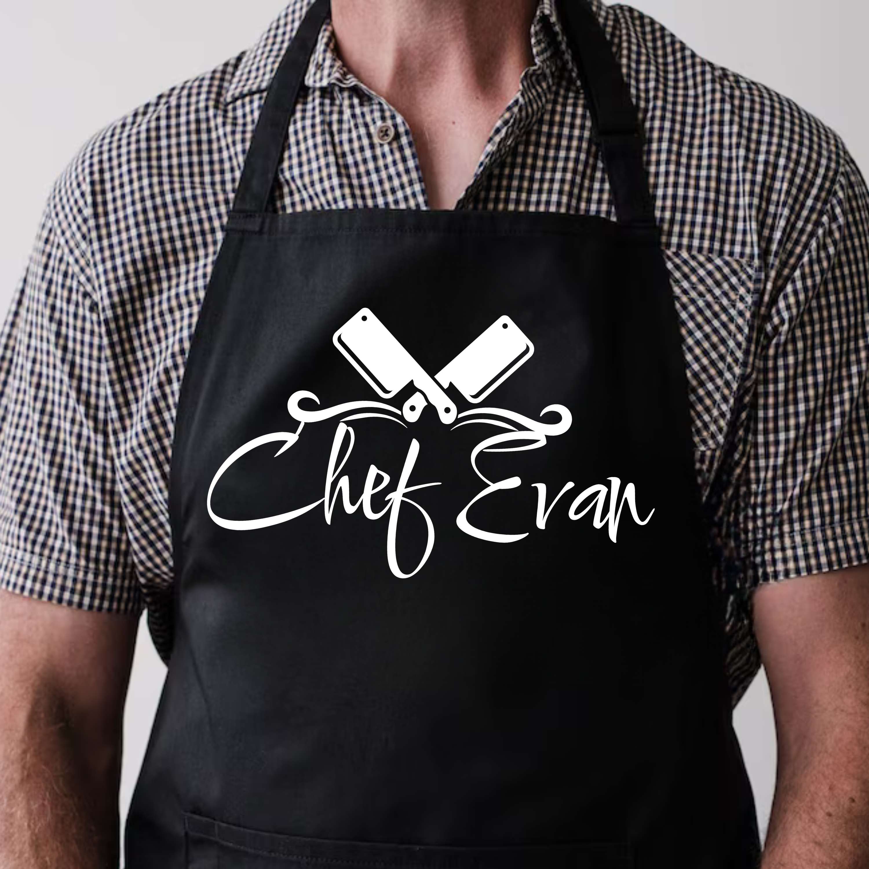Person wearing a black apron with 'Chef Evan' text and knife design.