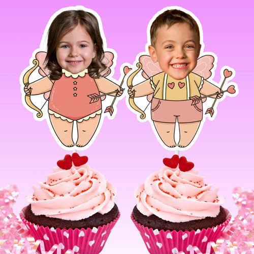 Two personalized Cupid photo cupcake toppers displayed on chocolate cupcakes with pink frosting, red heart decorations, and pink heart-print wrappers. One topper features a smiling girl in a coral Cupid outfit, and the other features a smiling boy in a yellow and pink Cupid outfit, both with pink wings, bows, and heart-tipped arrows against a bright pink background.