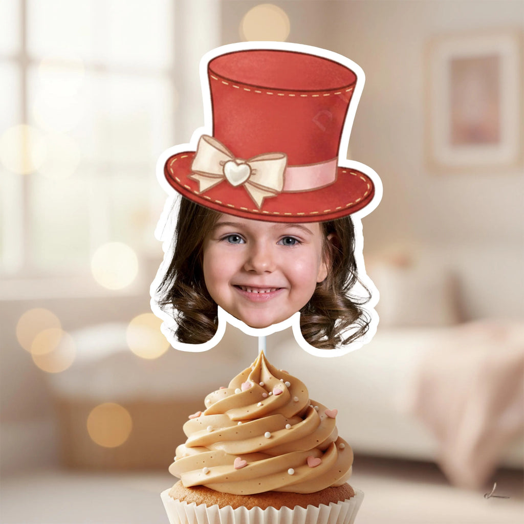 Personalized photo cupcake topper featuring a baby’s face wearing a red top hat with cream bow, displayed on a white frosted cupcake with pink heart accents and rose backdrop. Perfect for Alice in Wonderland tea parties, Mad Hatter birthday themes, romantic garden parties, and whimsical love-inspired celebrations.