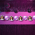 Purple disco ball decorations with a person's face cutout on a pink background