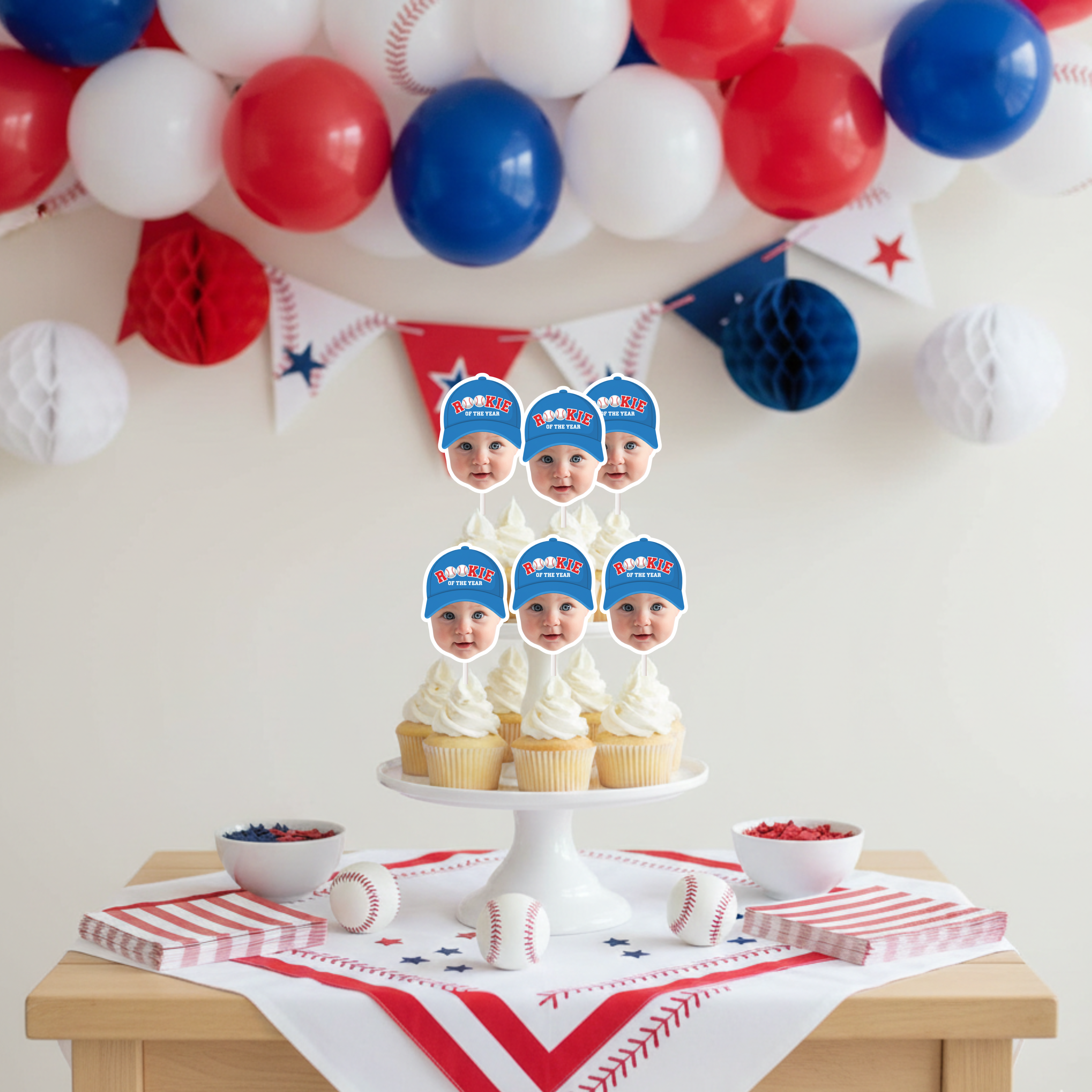 Baseball first birthday dessert table featuring Rookie of the Year photo cupcake toppers on a tiered stand with red white and blue balloon arch, All Star party decorations and little slugger themed setup.