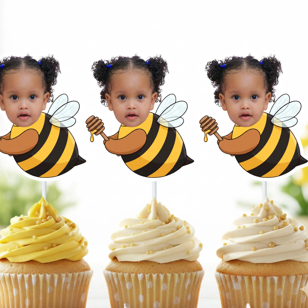 Three cupcakes with bee-themed toppers featuring a child's face, on a white background.