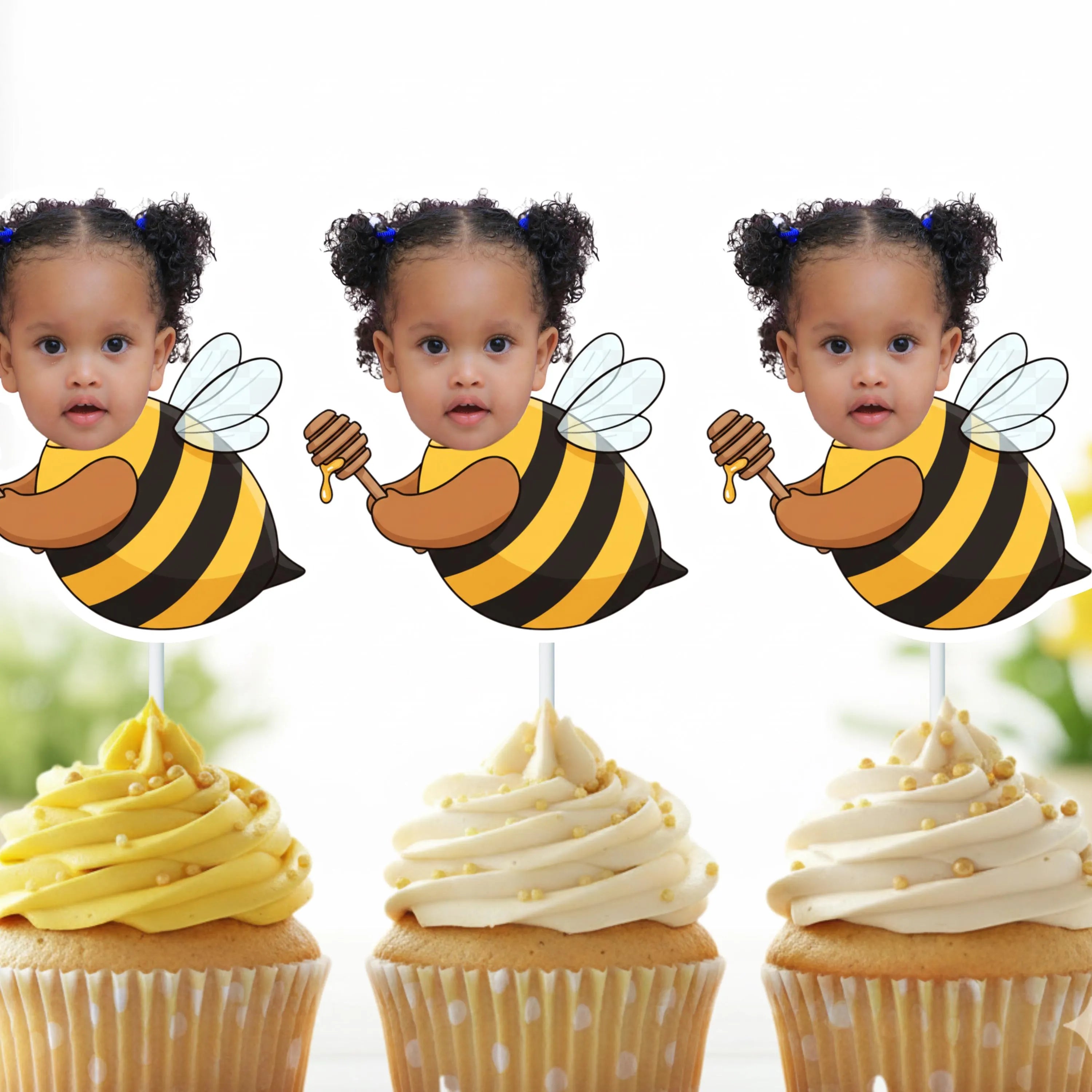 Three cupcakes with bee-themed toppers featuring a child's face, on a white background.