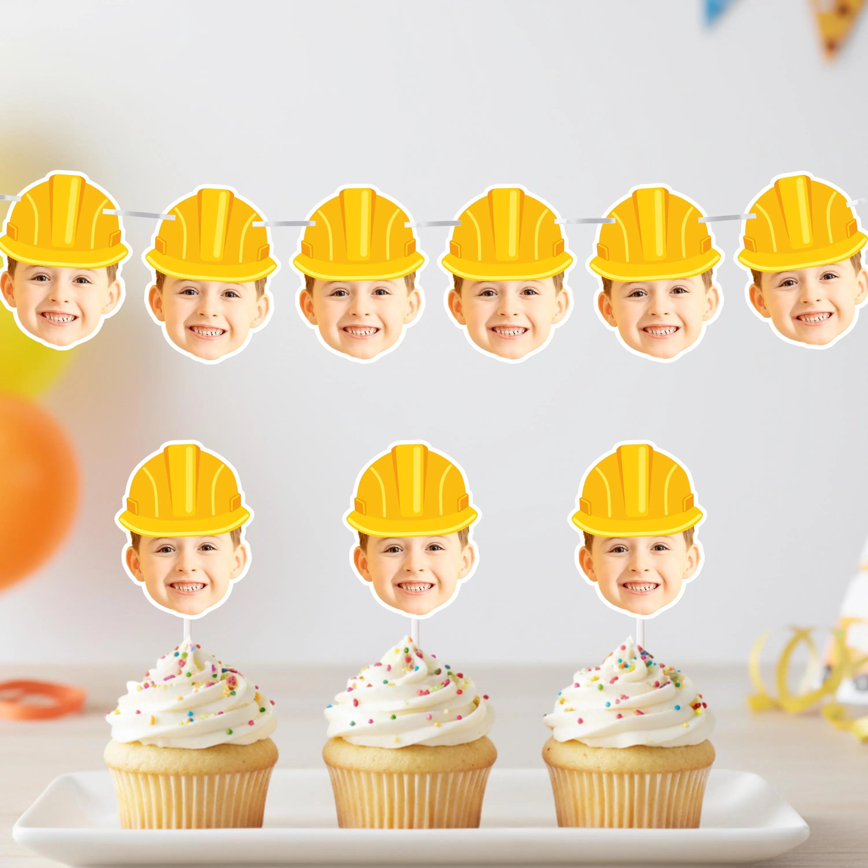 Cupcakes with yellow construction hats on top, set against a white background.