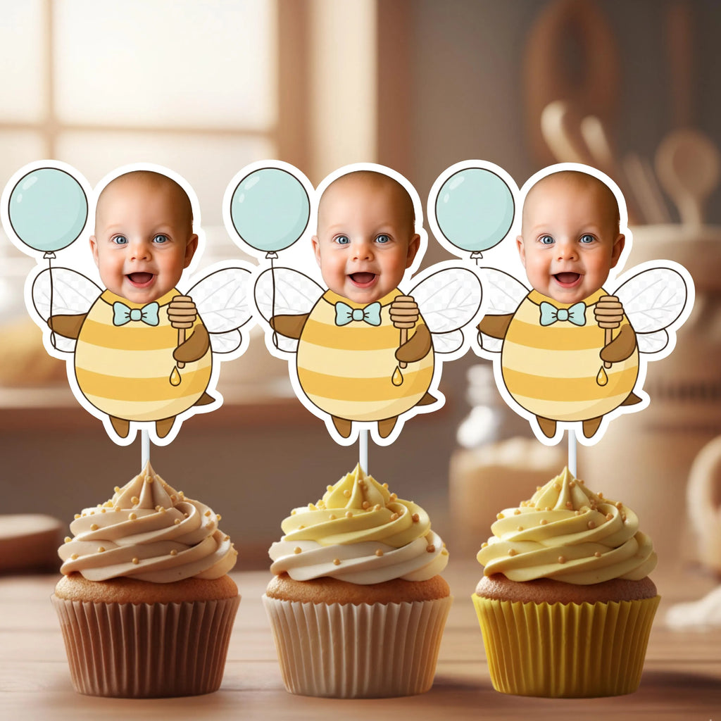 Three cupcakes with baby-themed toppers on a wooden surface.
